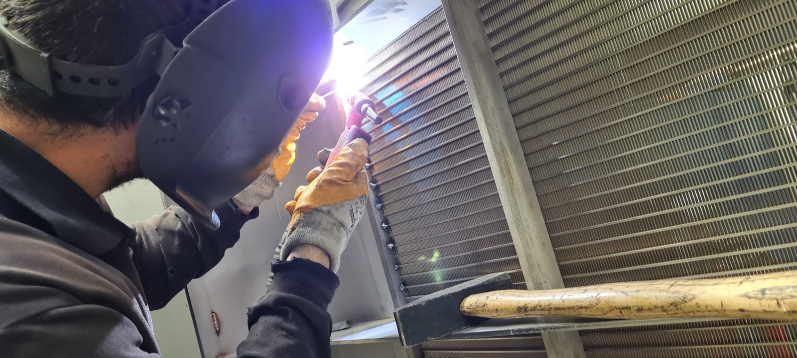Skilled technician performing manual welding on a stainless steel wedge wire screen panel
